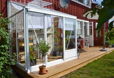 Miljøbillede af Midi drivhuset, med hvidlakeret aluminium, monteret på væg.