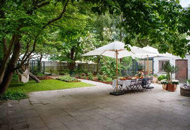 Udestue og terrasse i en have.
